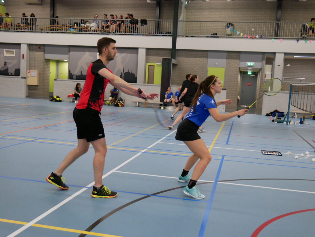 Gemengd dubbelkoppel op het badmintonveld, gefotografeerd tijdens de service