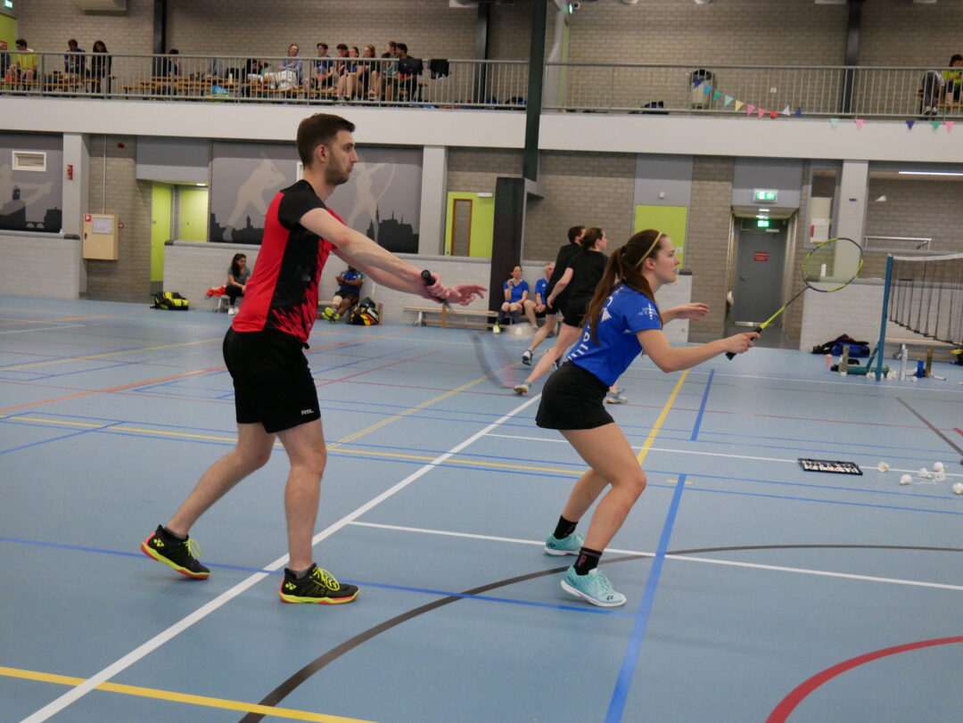 Gemengd dubbelkoppel op het badmintonveld, gefotografeerd tijdens de service