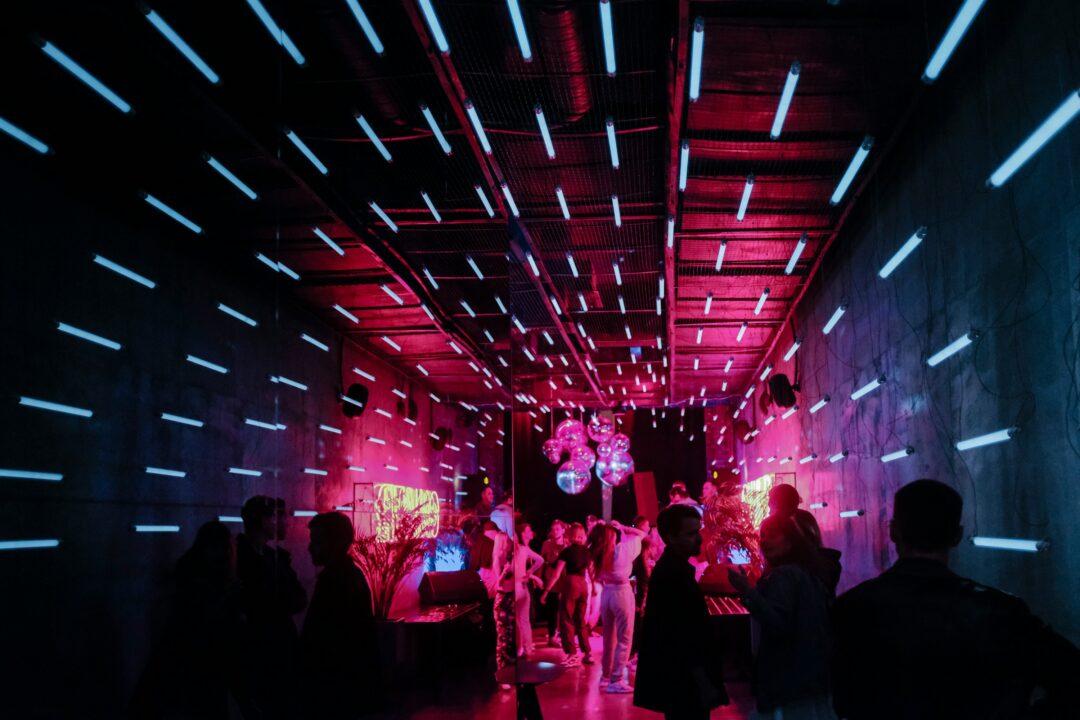 Feestende mensen in een discotheek, met veel discolampen.